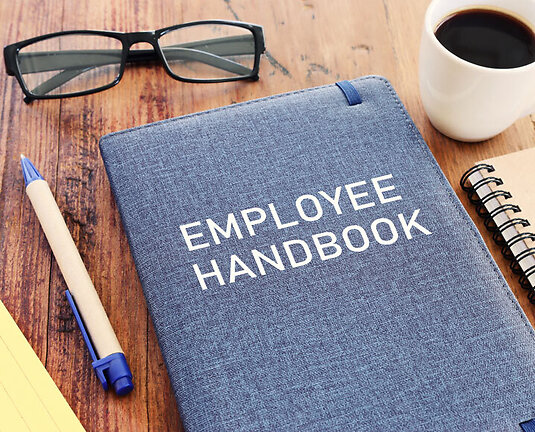 Concept image of employee handbook over wooden office table. top view