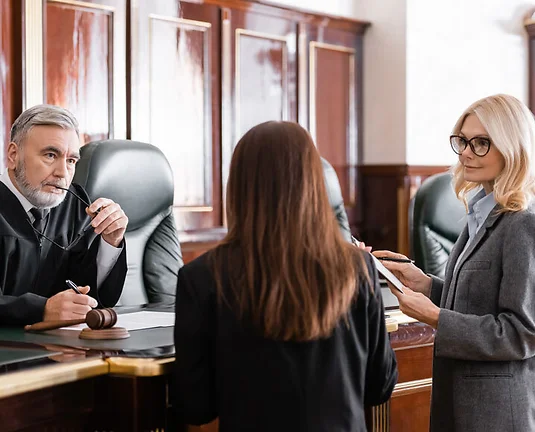 thoughtful judge holding eyeglasses listen to prosecutor standing near attorney in court
