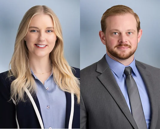Two attorneys, man and woman, wearing business attire smile at camera