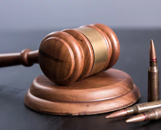 Wooden gavel and pounding block on grey background with bullet casings standing