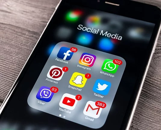 Phone with numerous social media app icons on the screen such as Instagram, Facebook, Pinterest, WhatsApp, Snapchat, Twitter, YouTube, Gmail, and Viber.