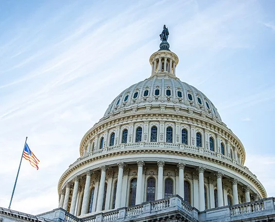 United States Congress Building in DC with an American flag outside.