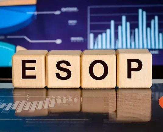 Wooden blocks spelling "ESOP" in front of colorful graphs and charts, emphasizing financial data and employee ownership plans.
