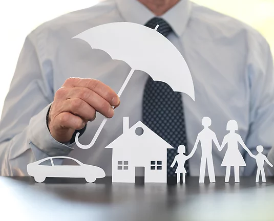 Man wearing shirt and tie holds white paper cutout umbrella above paper cutouts of car, home and family members