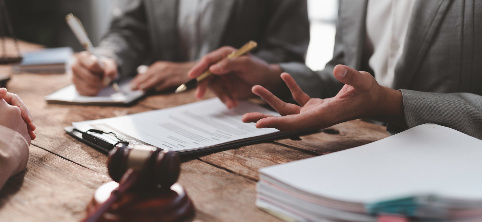 Hands holding pens as they review contracts