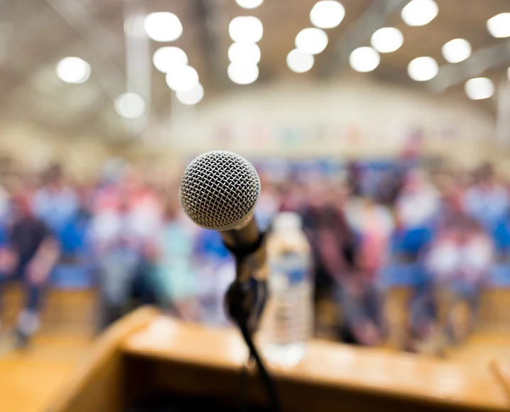 Microphone on podium in front of blurred image of crowd