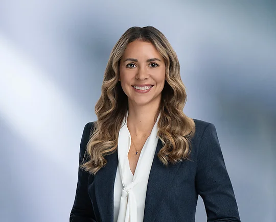 Blonde attorney, Lisa Gallagher, smiles at camera, wearing white blouse and blue sport coat.