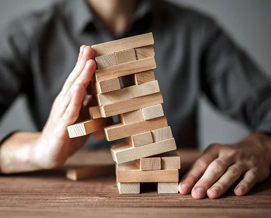 Person stopping a jenga tower form falling over.