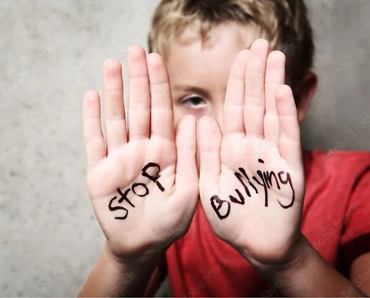 A boy wearing a red shirt with the words "Stop Bullying" written on his palms.