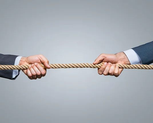 Two hands in business suits pulling on a rope, symbolize conflict, business problems, teamwork problem