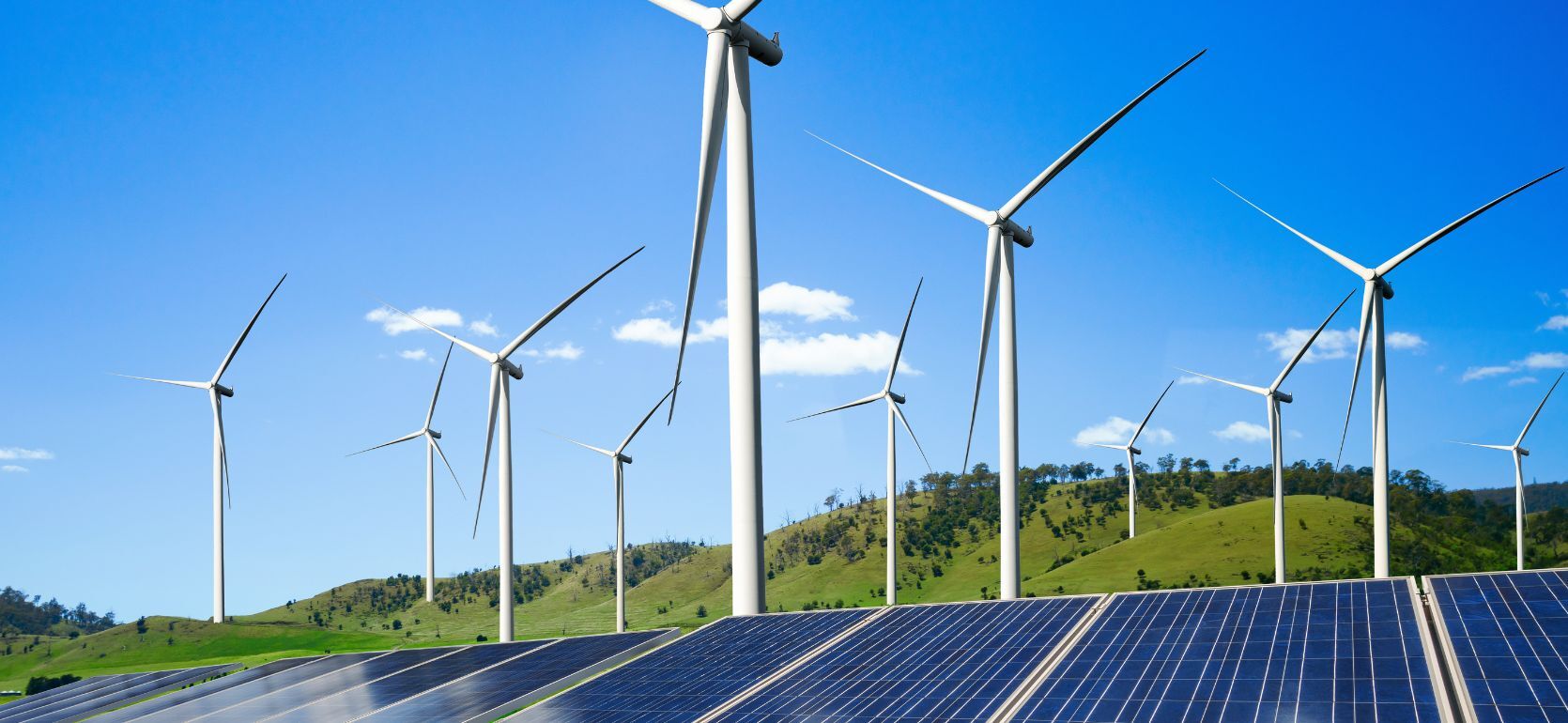 Wind turbines and solar panels with a blue sky in the background.