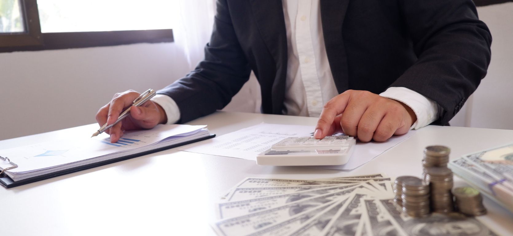 Someone typing on a calculator and writing on paper.