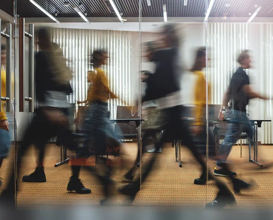 A picture of blurred people walking up and down a hallway.